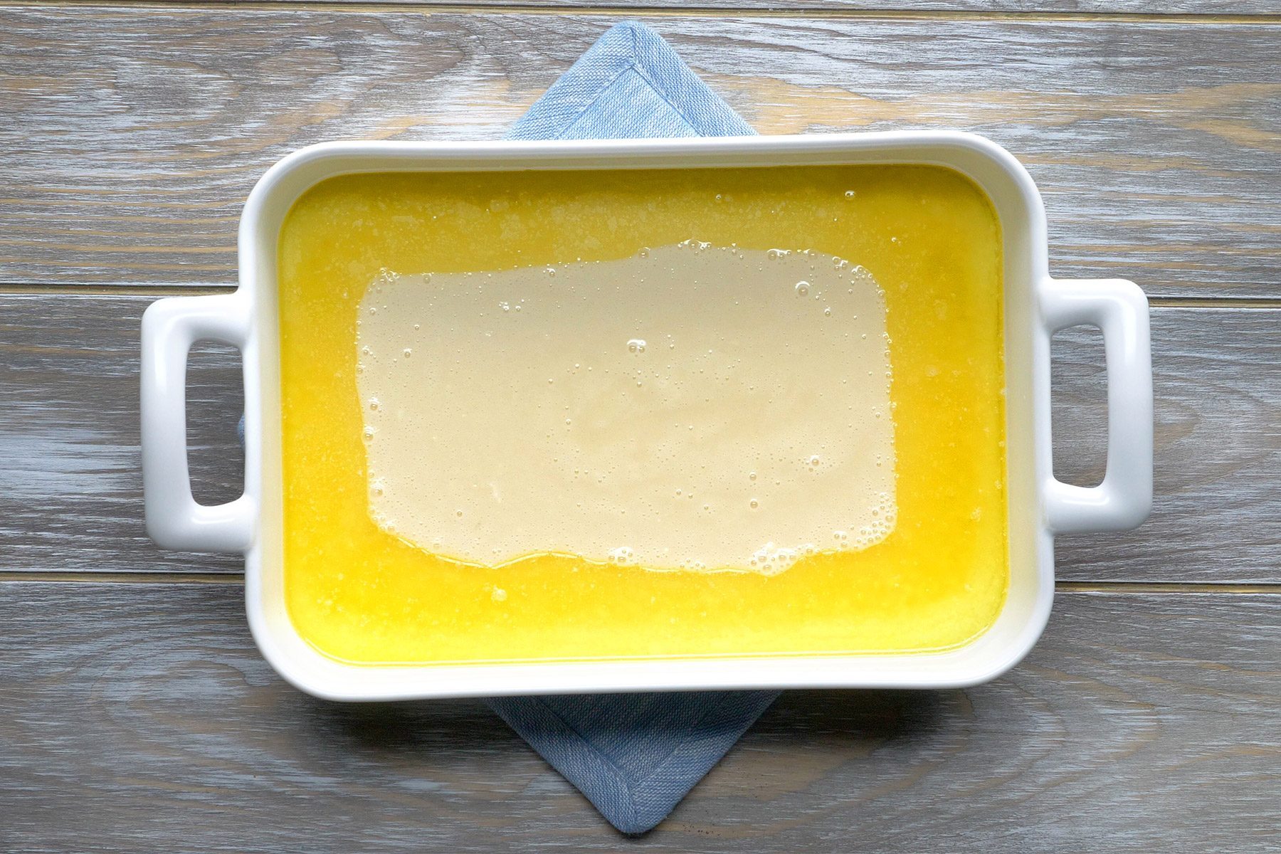overhead shot; wooden background; pour over melted butter over the mixture in a baking dish;