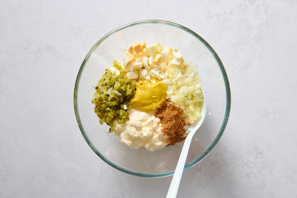 Mixing hard boiled eggs with the other ingredients in a large bowl