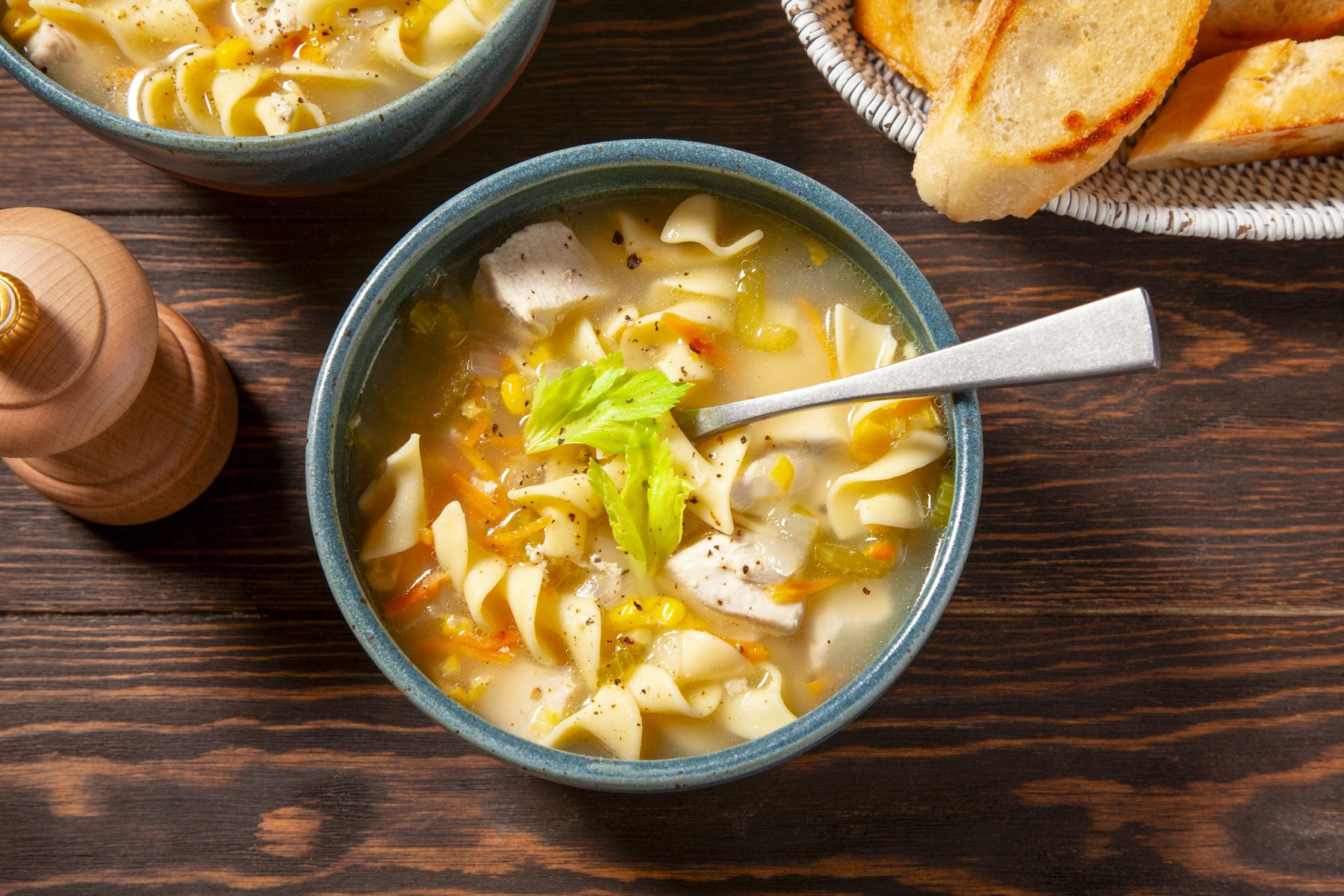 A bowl of Chicken Corn Soup topped with celery leaves and cracked pepper