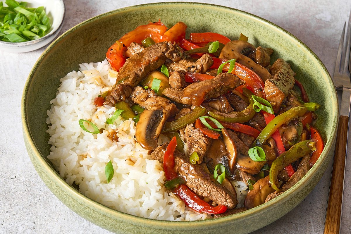 Closeup of Chinese pepper steak served with rice and topped with scallions