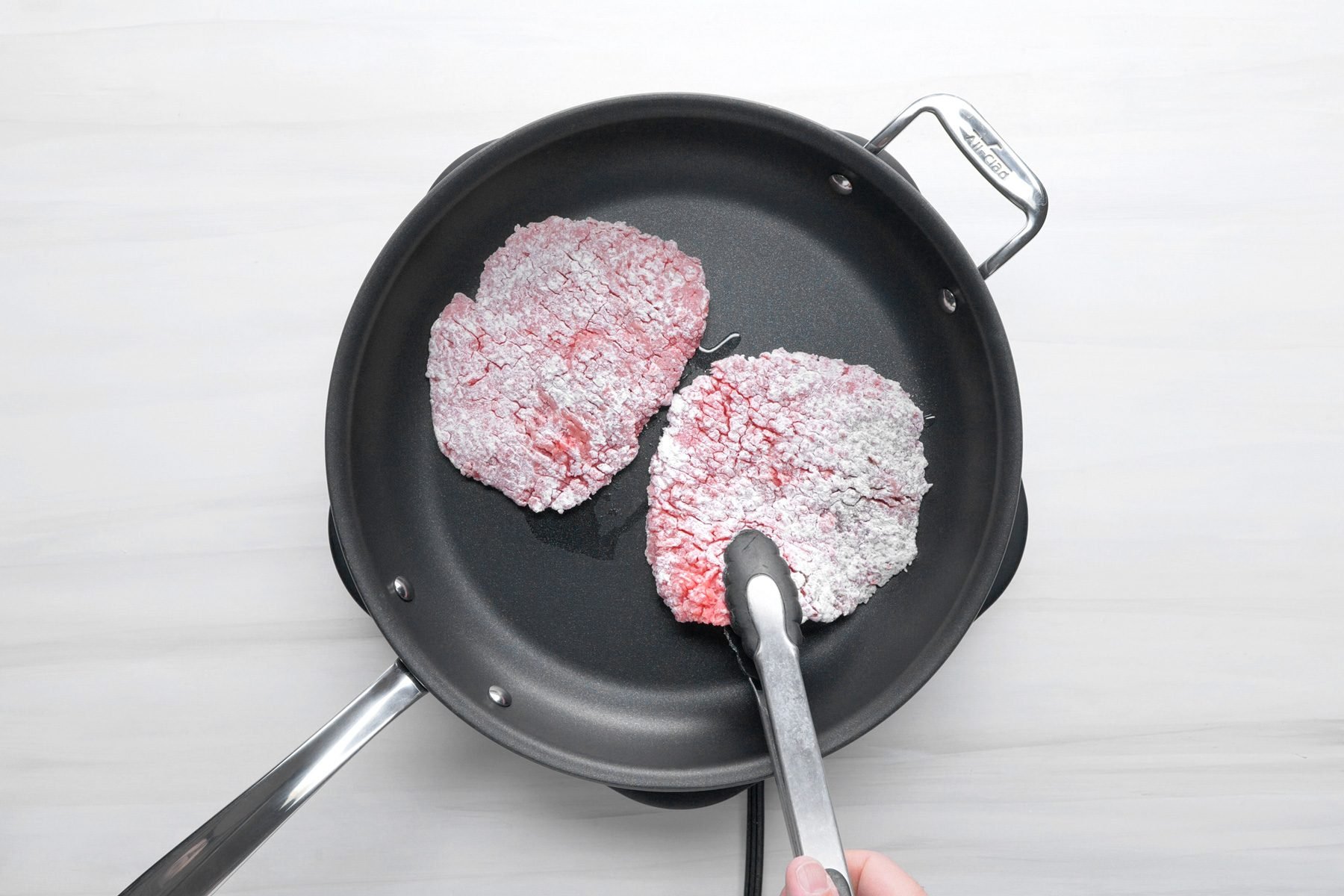 Beef cube steaks cooking in oil in a large skillet