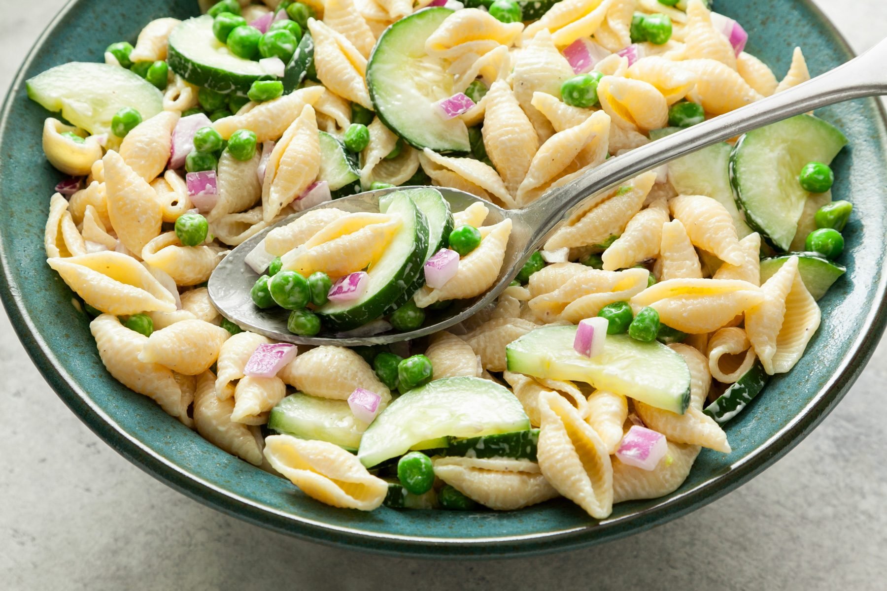 Cucumber Pasta Salad mixed with cucumbers, onions and peas in a bowl