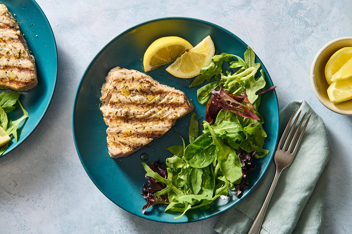 Overhead shot of grilled tuna steak on a plate with side salad