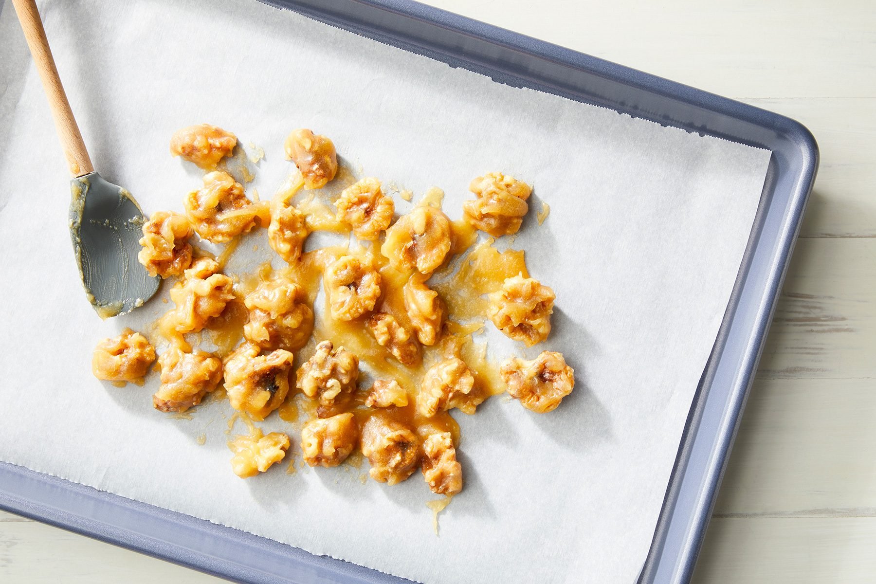 overhead shot; white background; Spreading walnut mixture onto parchment covered sheet pan;