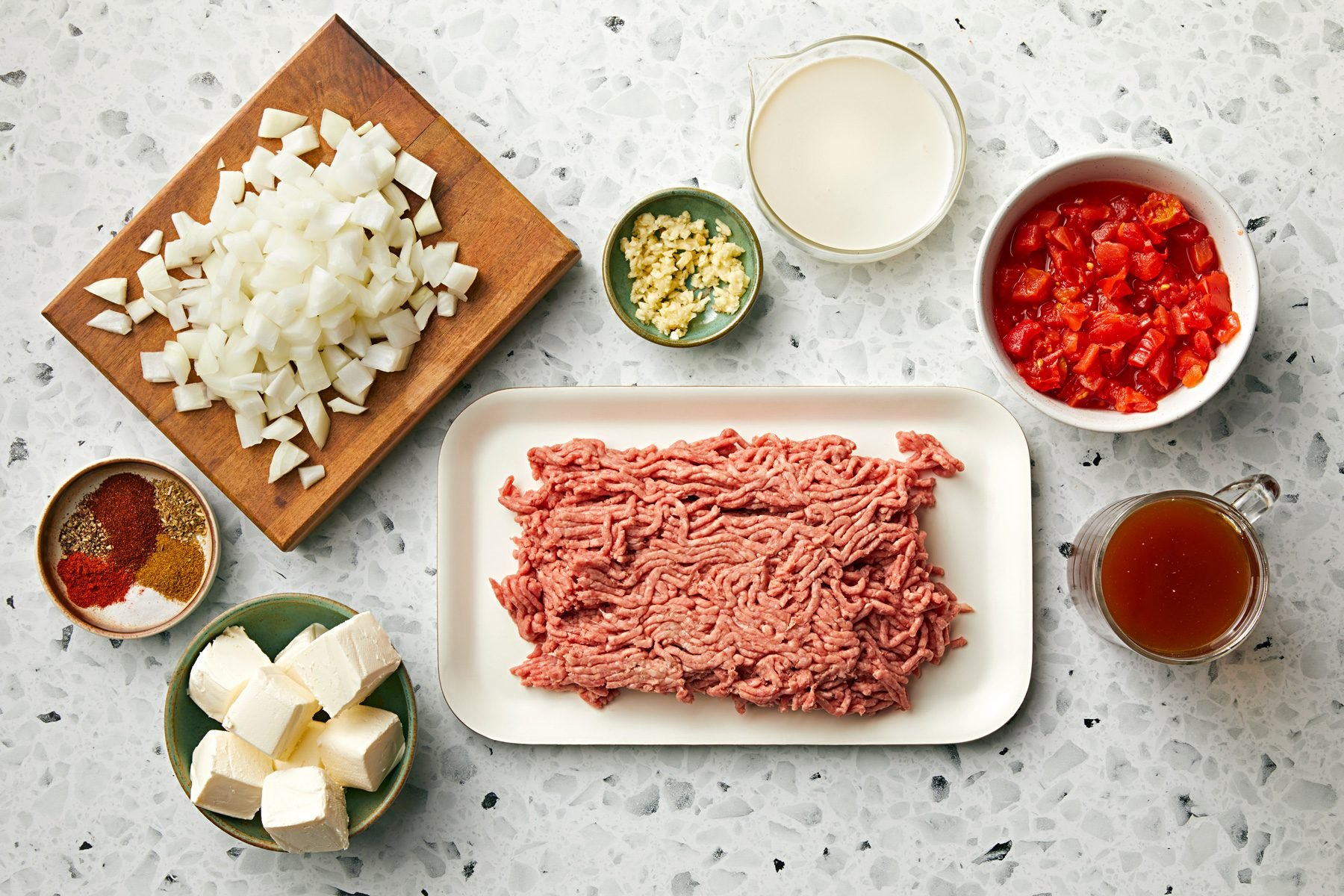 Raw ground beef in a white tray alongside other ingredients for Keto Taco Soup