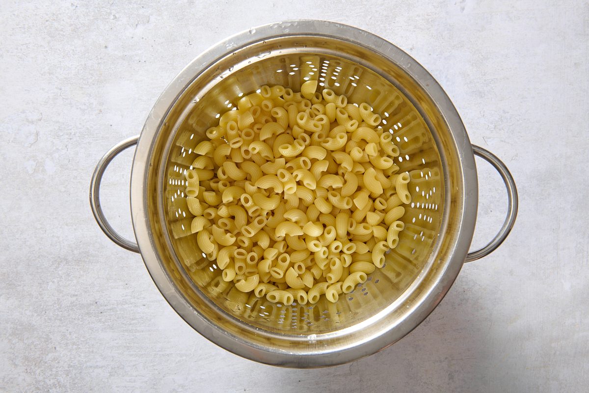 Cooked macaroni draining in a colander