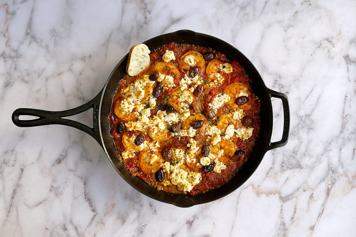 Taste of Home's shrimp saganaki in a cast iron skillet on a white marble table.