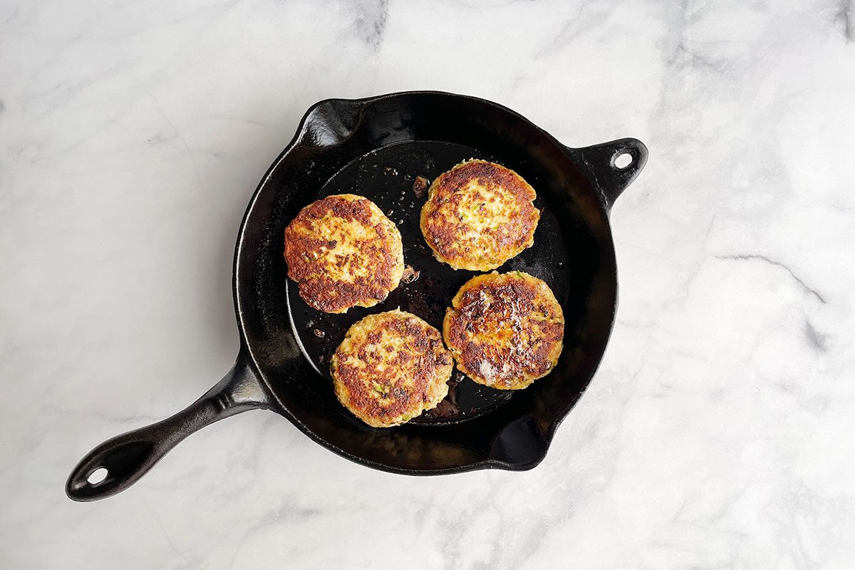 Frying Taste of Home's shrimp burgers recipe on a cast iron skillet .