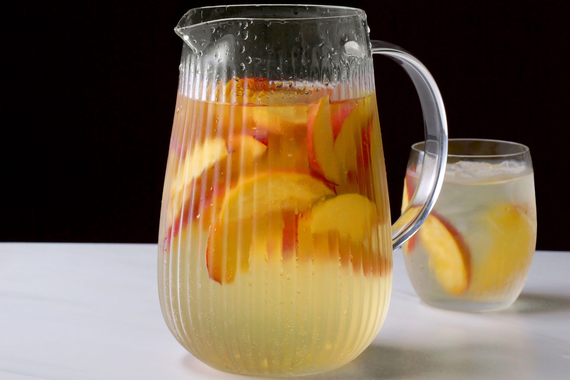 Peach Sangria in a large jar with peach slices