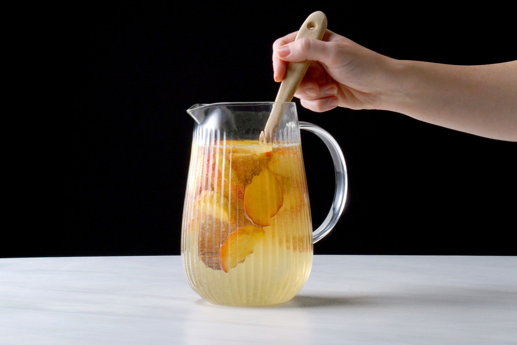 Stirring peach sangria with a wooden spoon