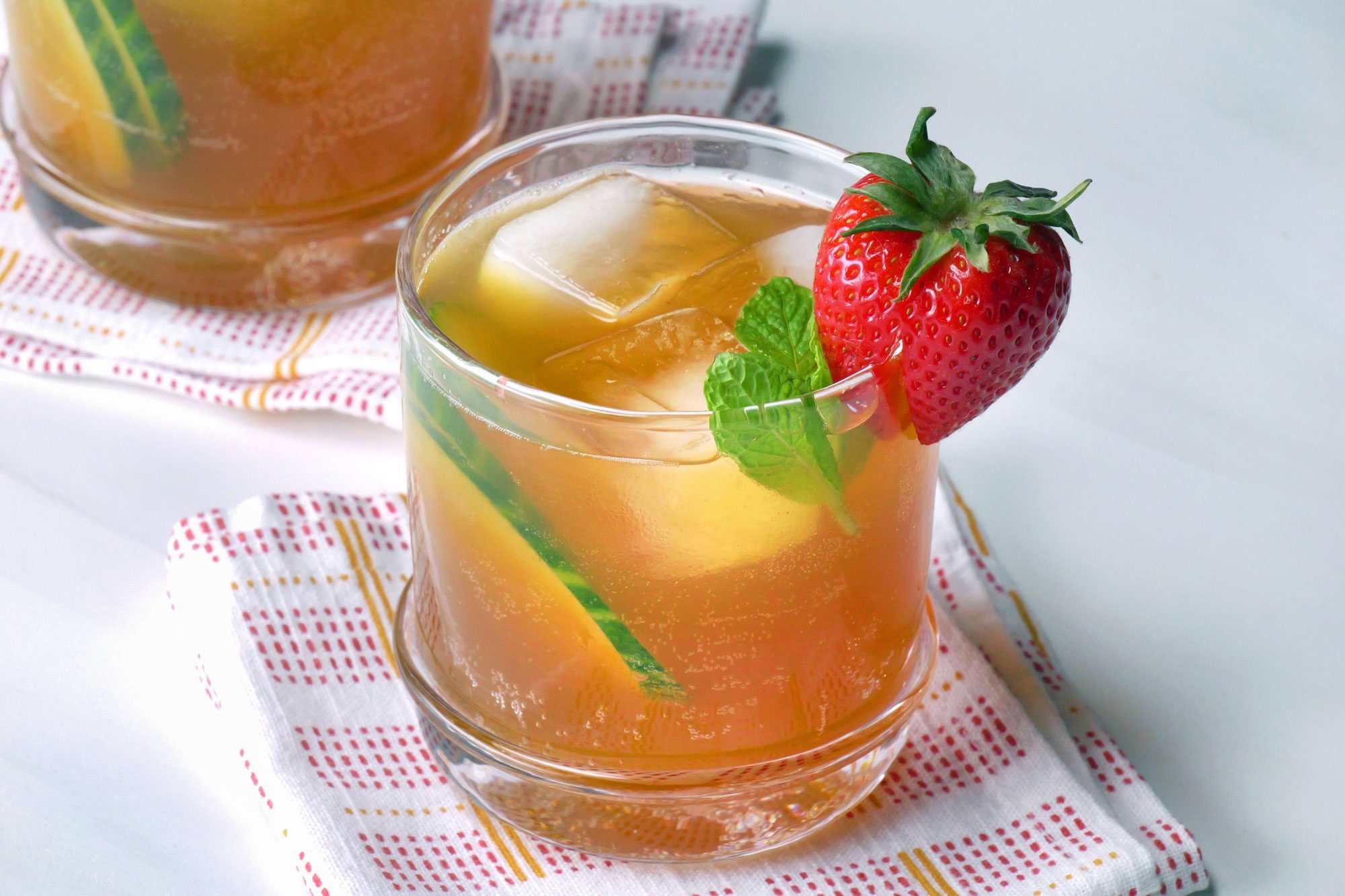 Pimm's mixture served into rocks glass garnished with cucumber, strawberry and mint