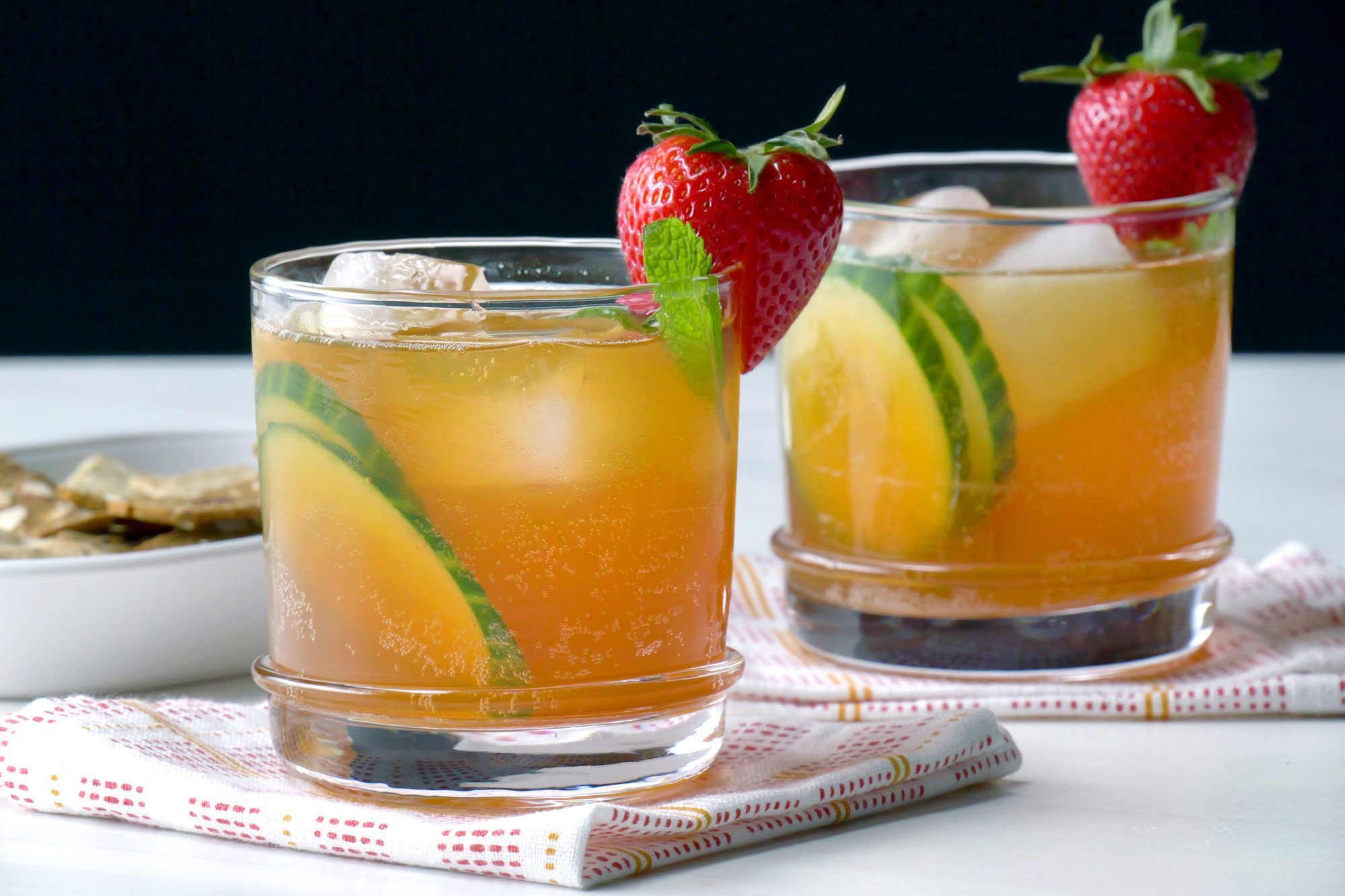 Pimm's mixture served into rocks glass garnished with cucumber, strawberry and mint