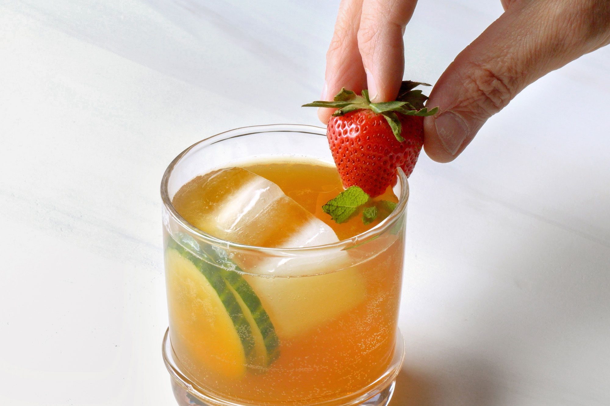 Garnishing the drink with cucumber, strawberry and mint