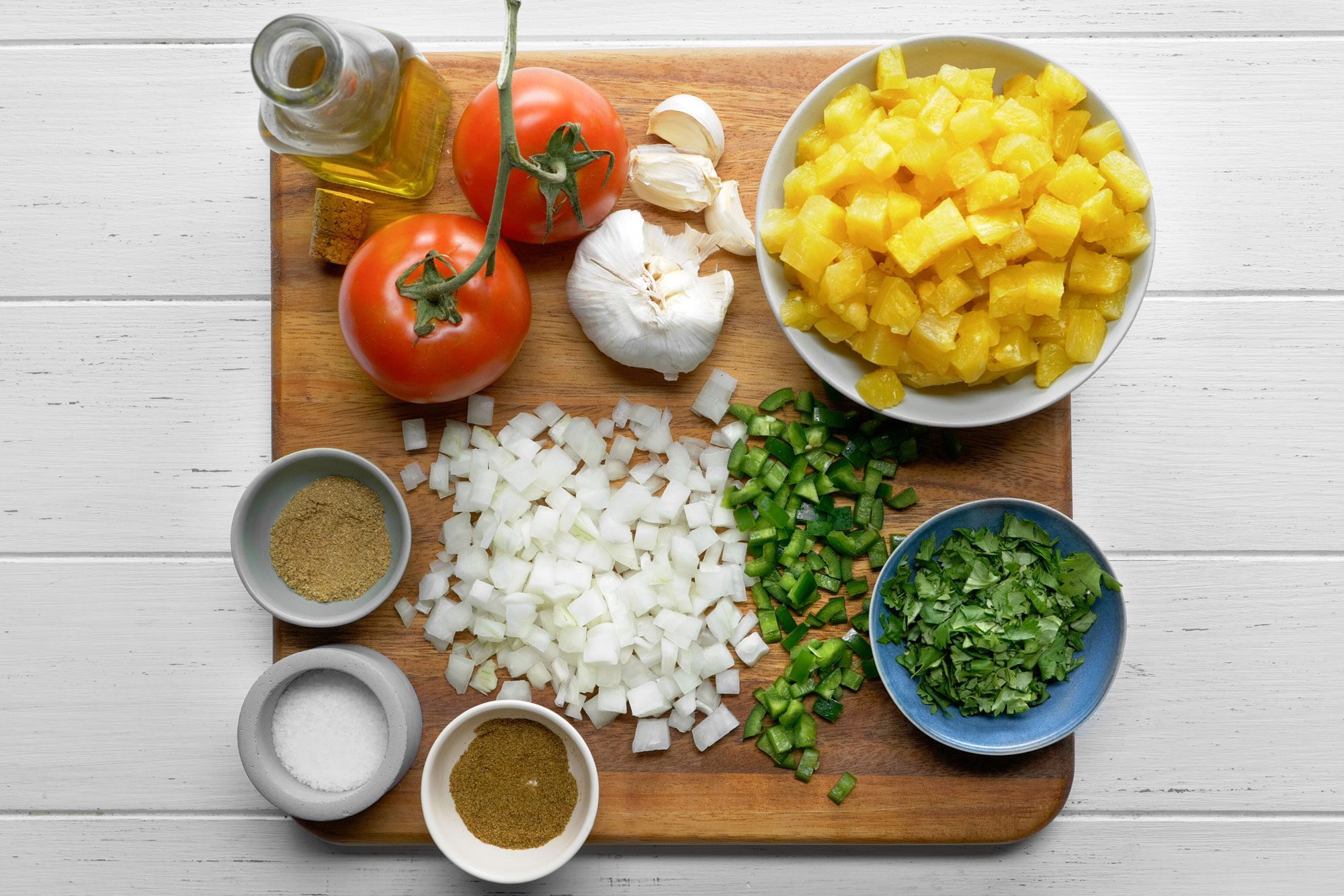 overhead shot; white background; pineapple salsa ingredients over wooden board;