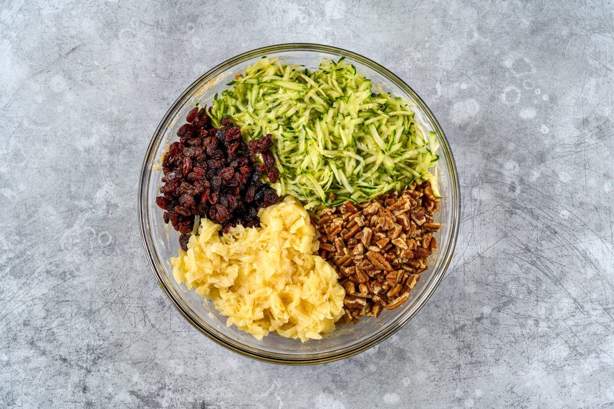 shredded zucchini, crushed pineapple, chopped nuts, and raisins in a bowl
