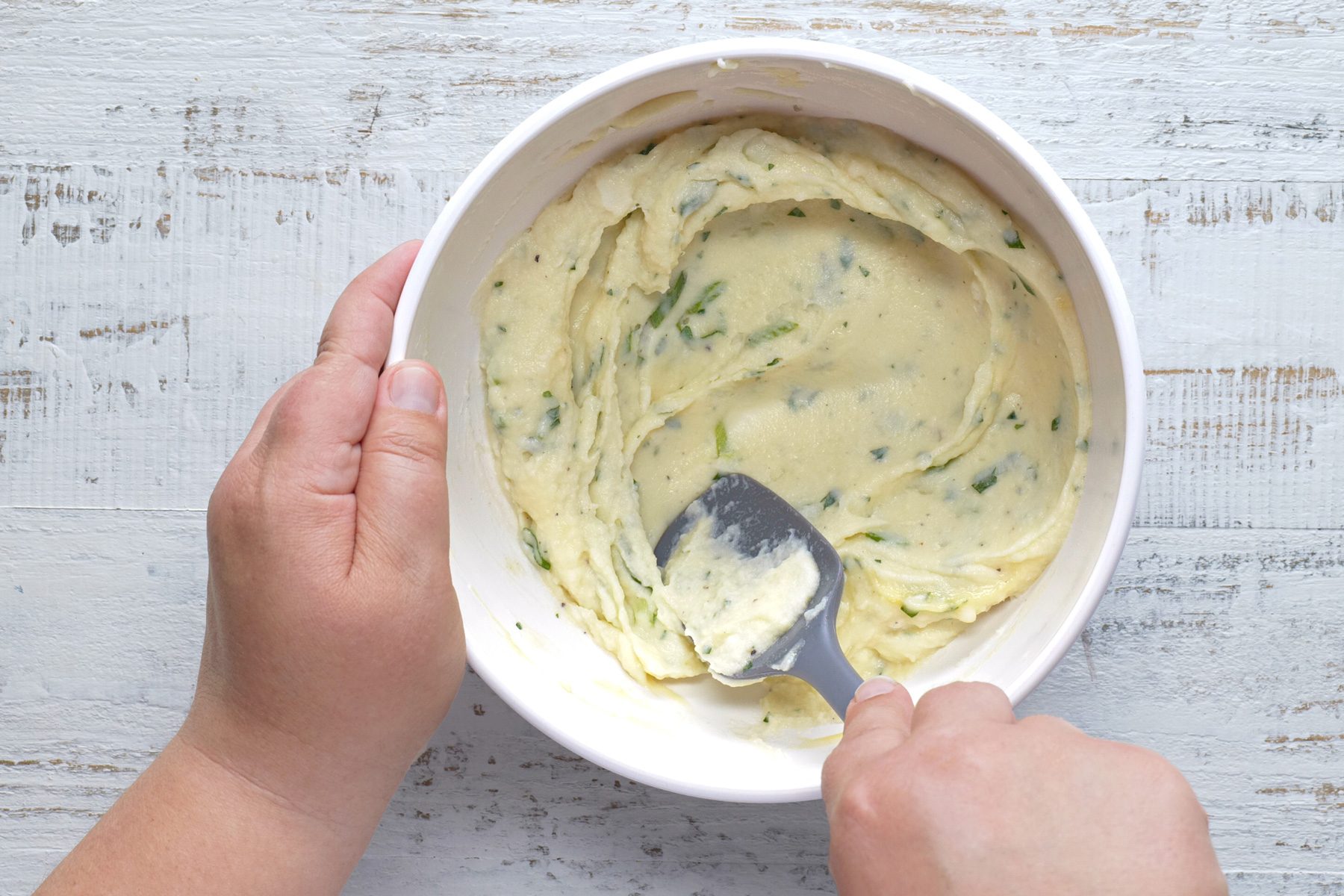 Combining ingredients in a bowl to make a pancake mixture using a spatula