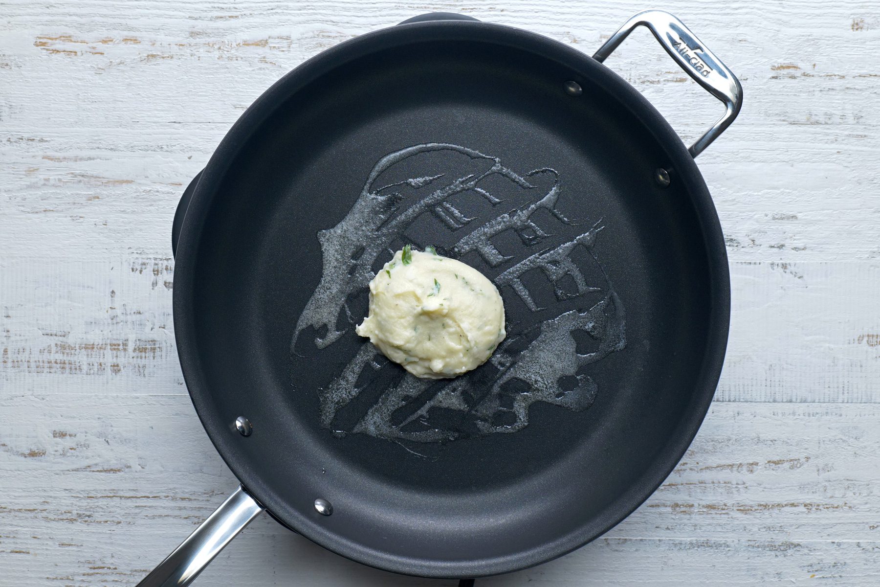 Butter sprayed skillet with a portion of pancake mixture on it