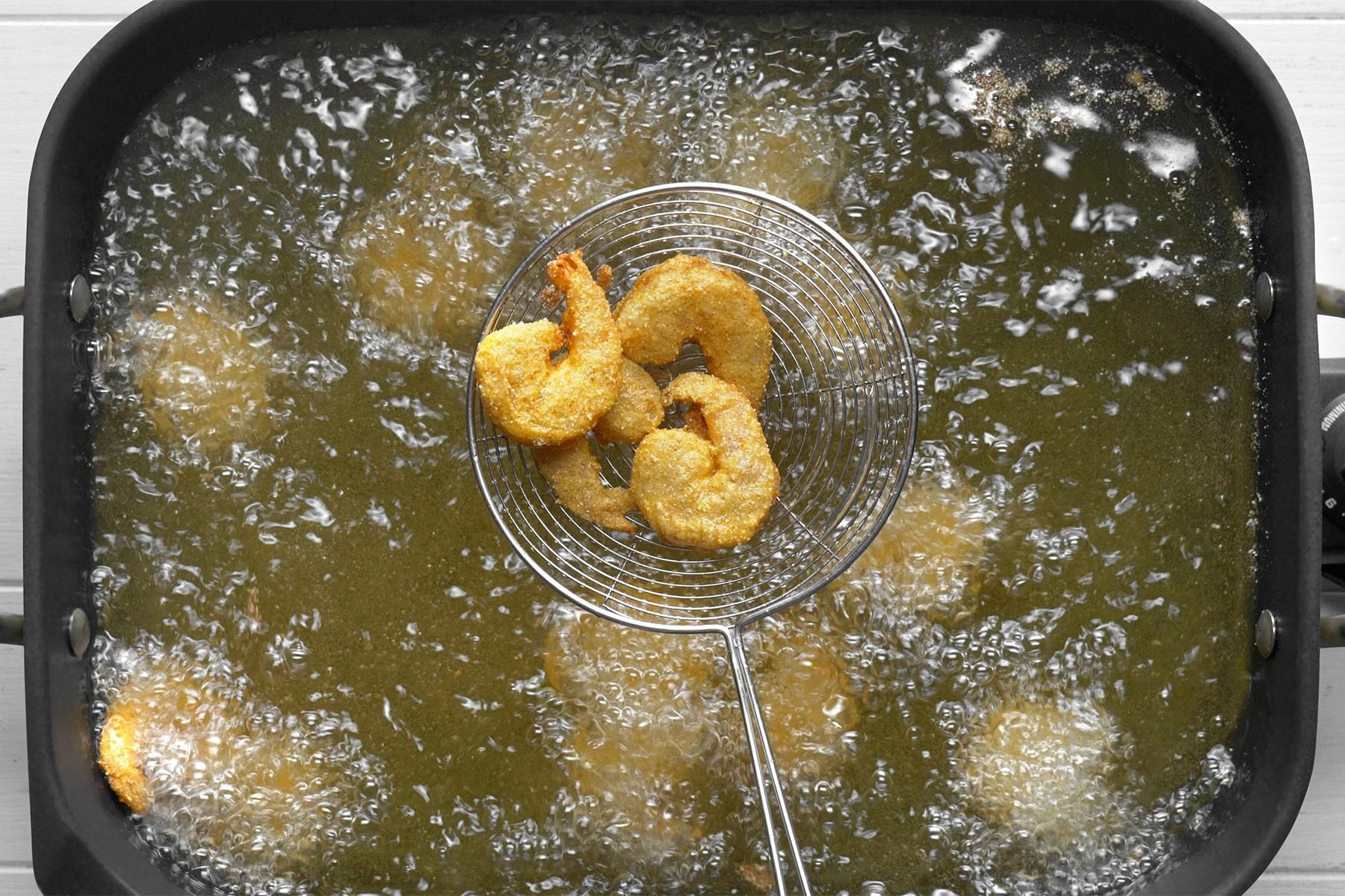overhead shot; white background; In an electric skillet or deep-fat fryer, Frying shrimp in batches until golden brown