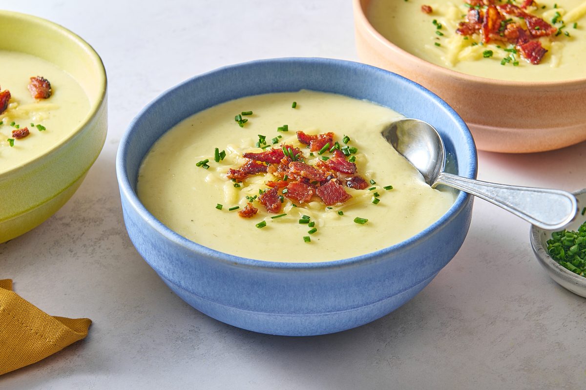 Closeup of a bowl of slow cooker potato soup topped with garnishes