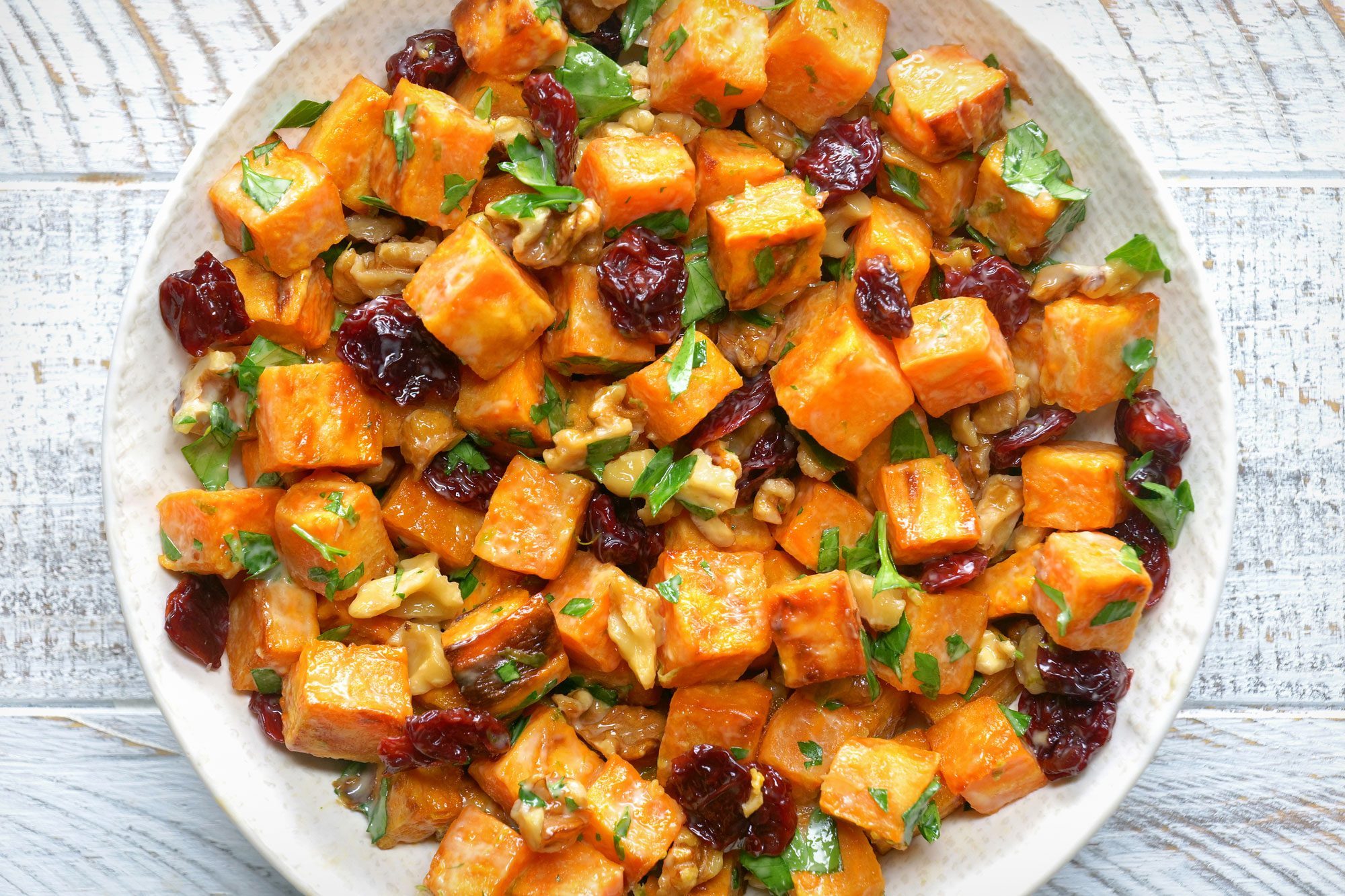 overhead shot of roasted sweet potato salad; white wooden background;