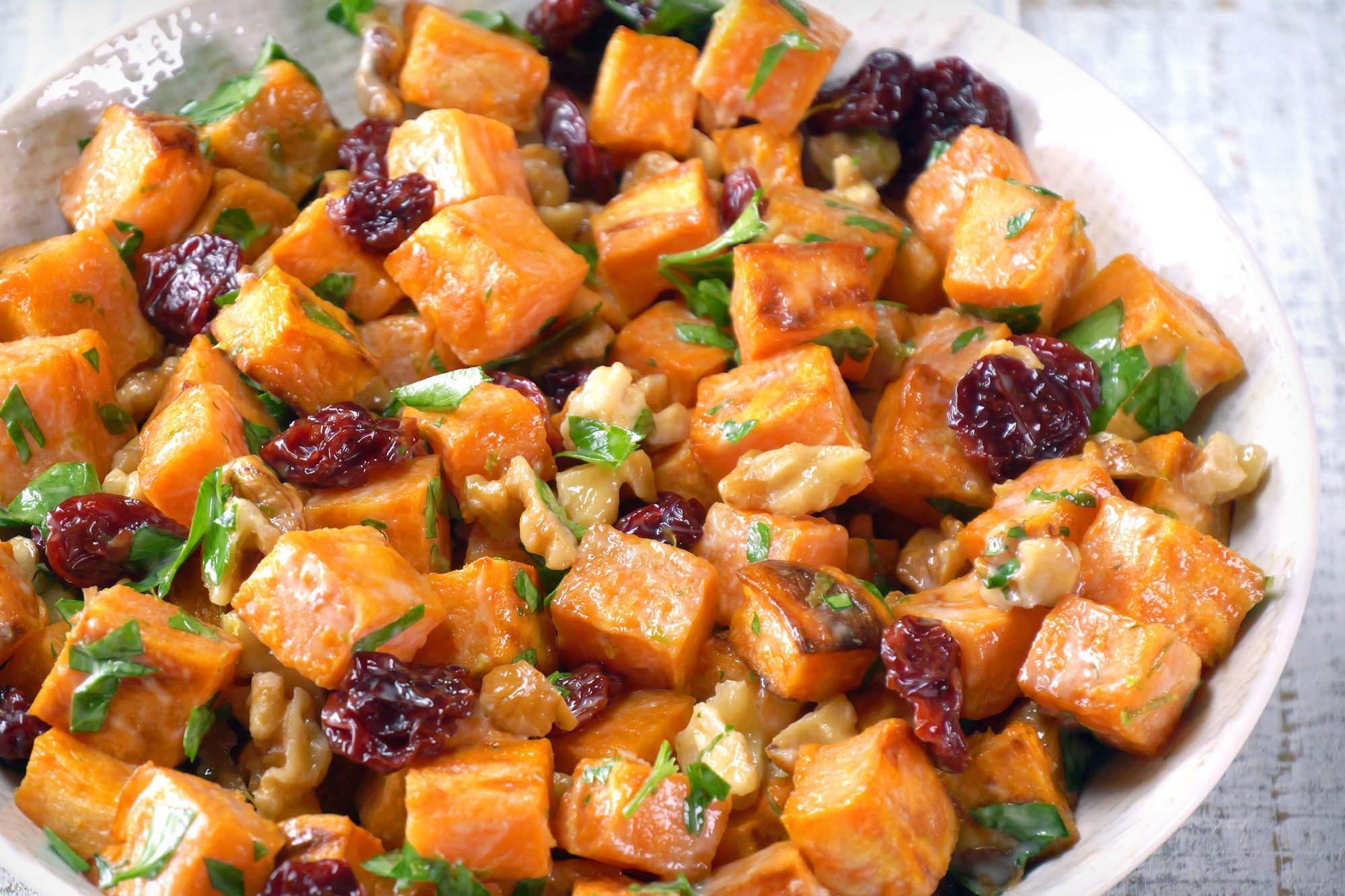 close shot of roasted sweet potato salad; white wooden background;