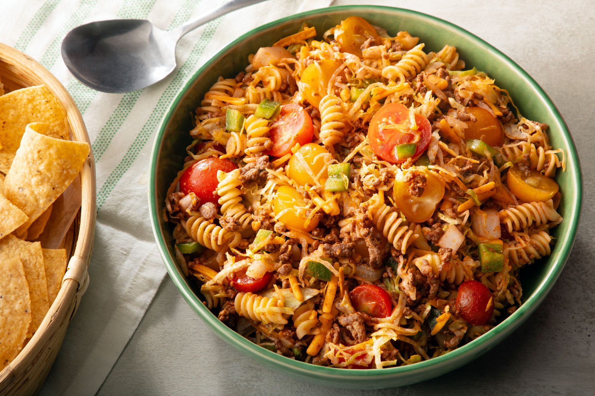 Taco Pasta Salad in green bowl on grey surface.