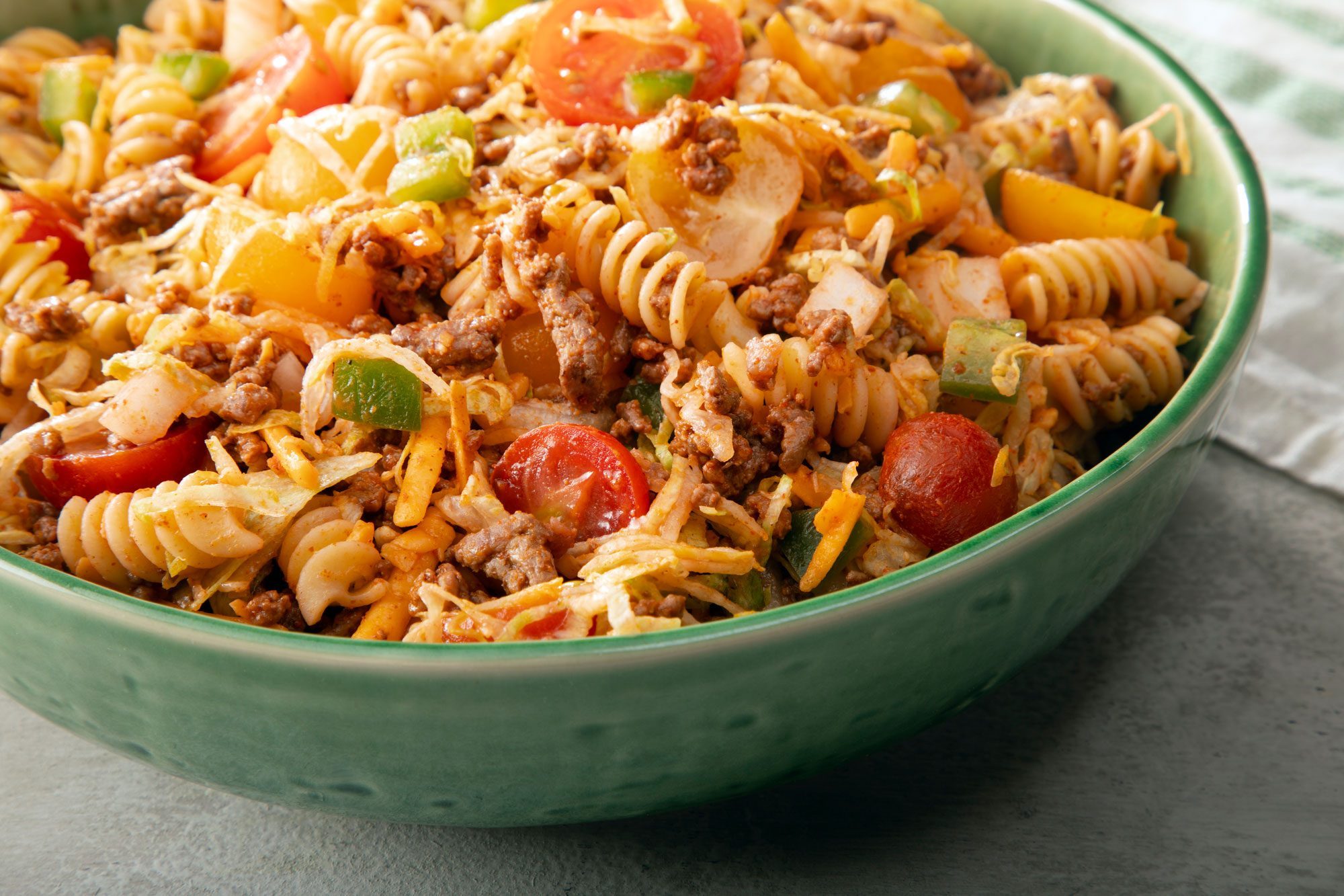 Taco Pasta Salad in green bowl on grey surface.