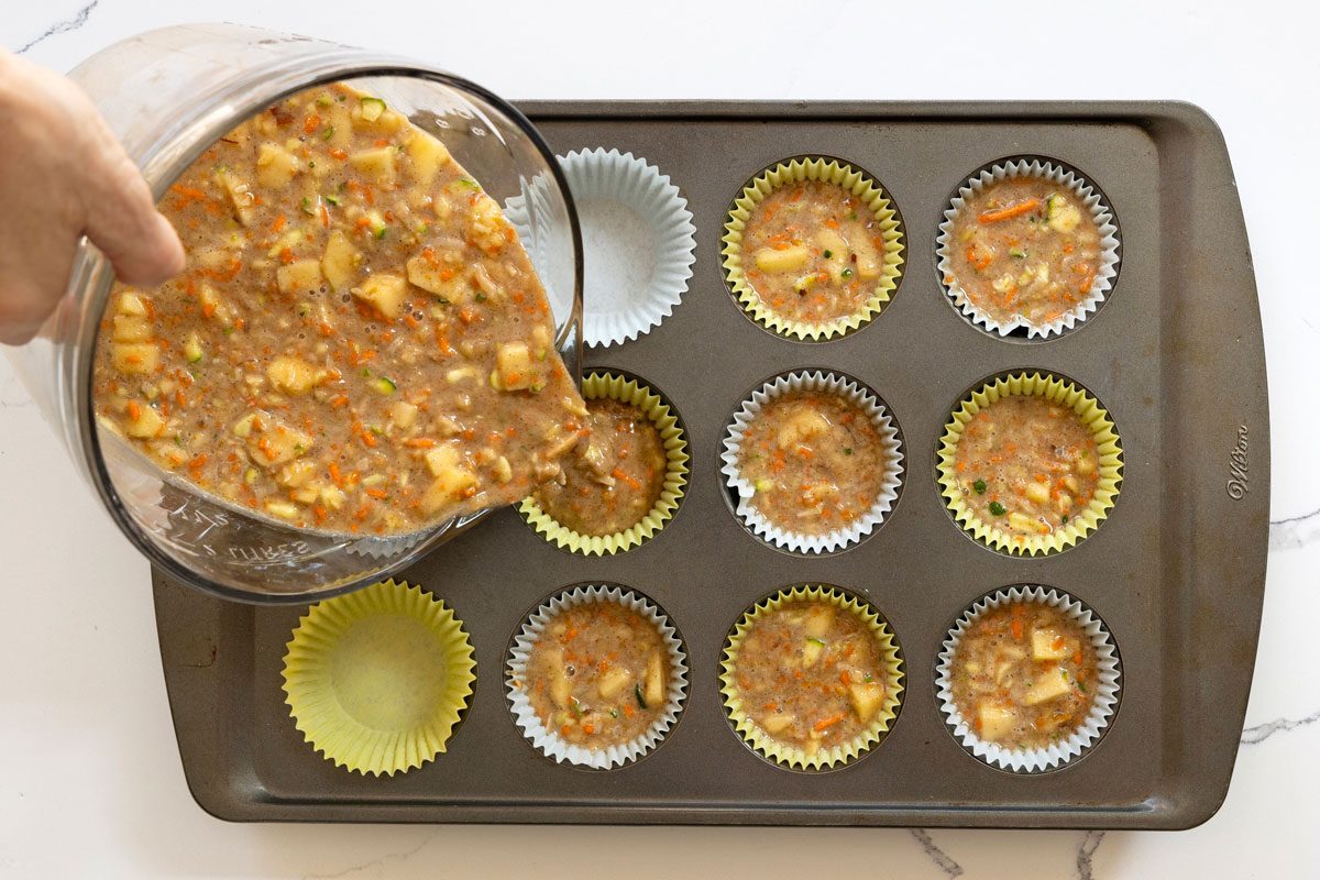 Pouring The zucchini carrot muffin Batter In Muffin tin