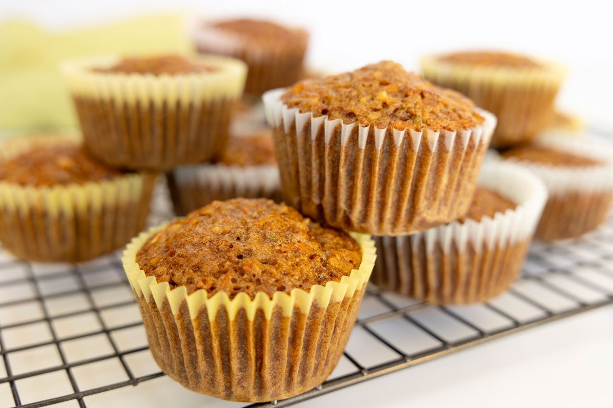 zucchini carrot muffins stacked on a cooling rack