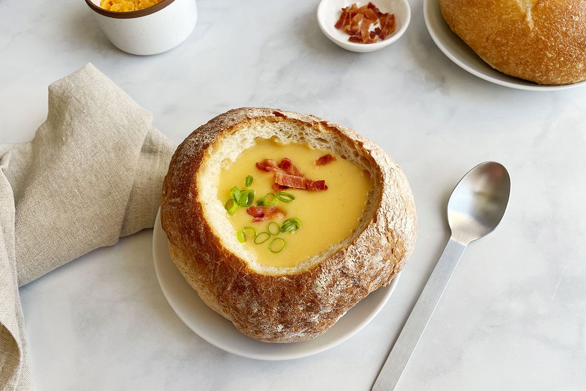 Taste of Home's Beer Cheese Soup in a bread bowl on a white marble background