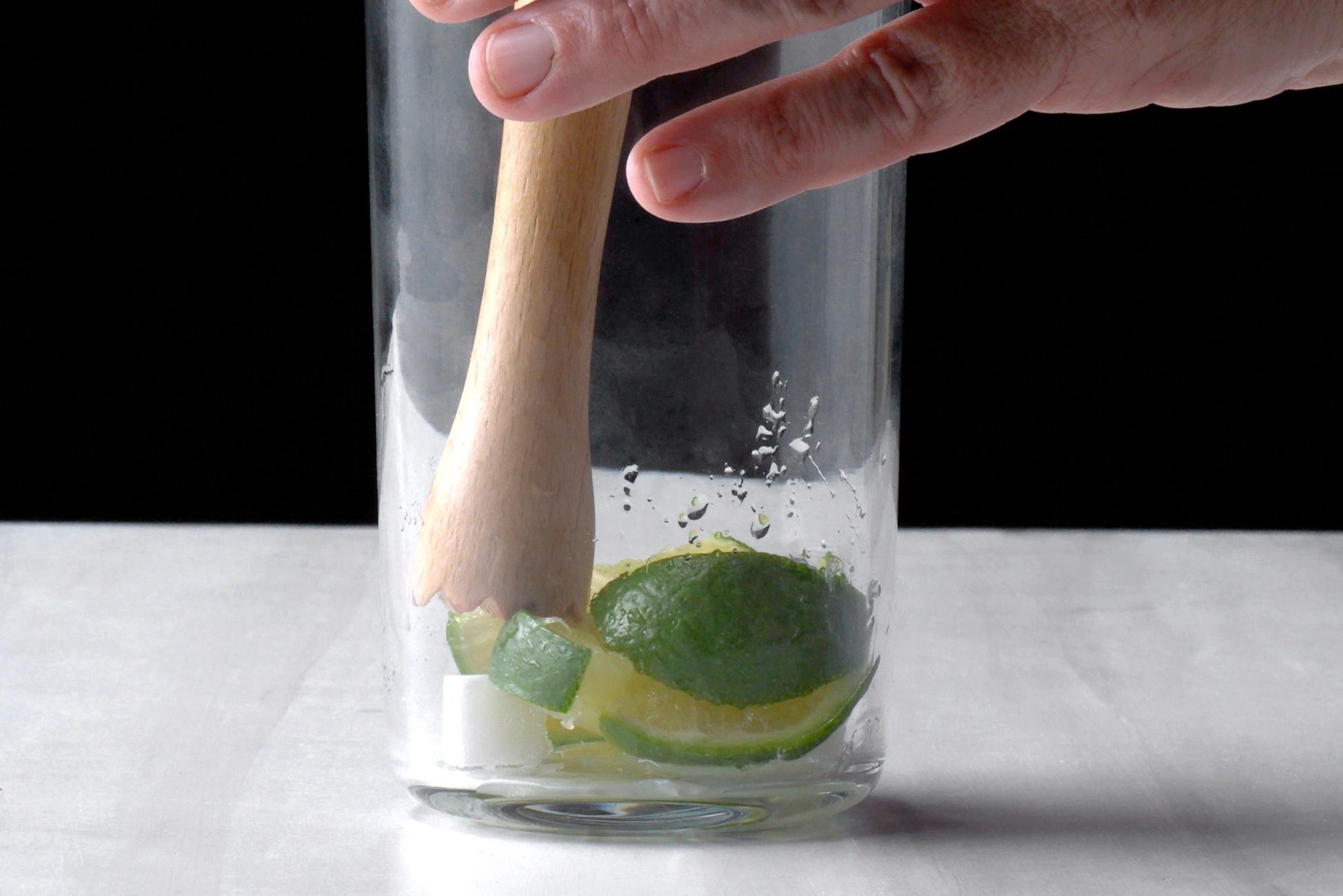 Muddle the lime and sugar cubes together in a cocktail shaker until combined