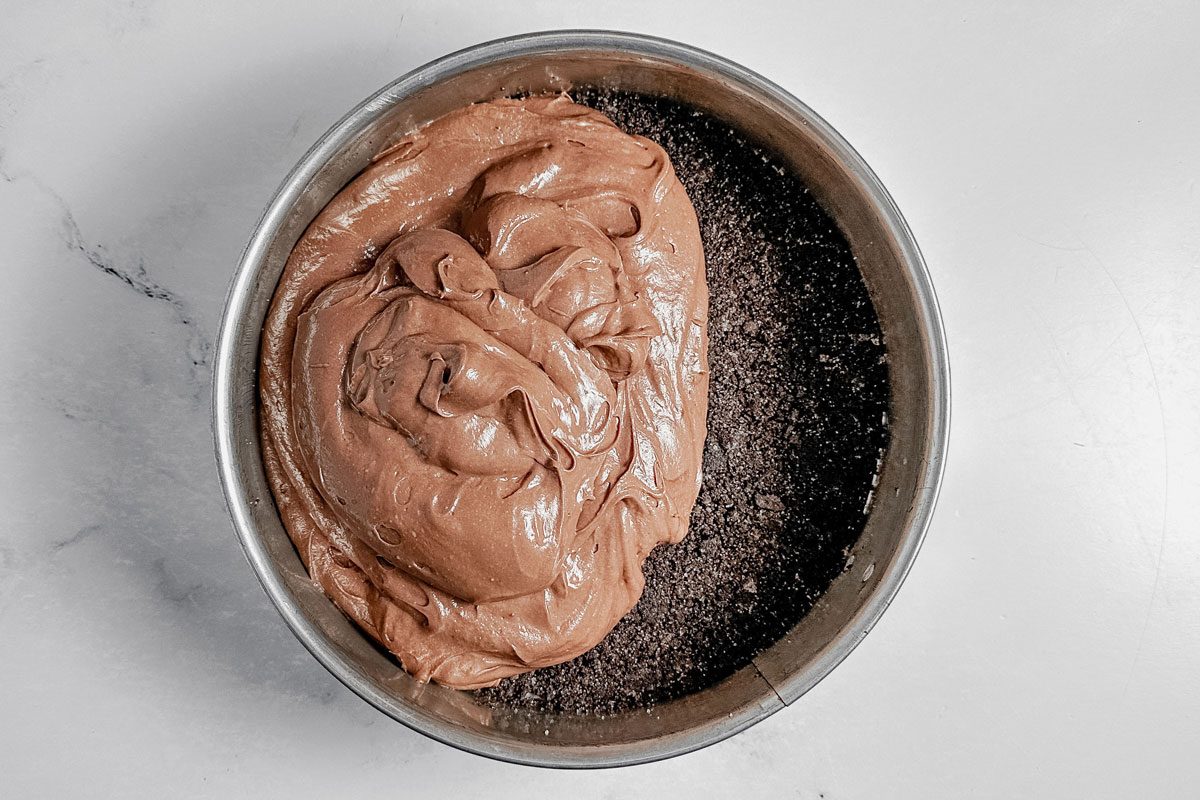 Unbaked filling and crust for Taste of Home chocolate cheesecake in a springform pan on a marble surface.