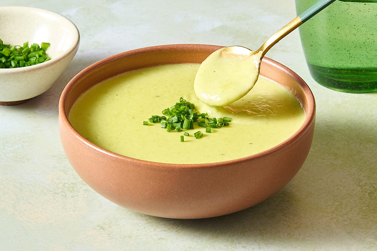 Closeup shot of a spoon dipping into a bowl of cream of asparagus soup