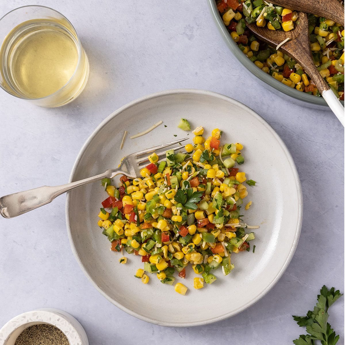 Corn salad served on a plate with serving bowl next to it.