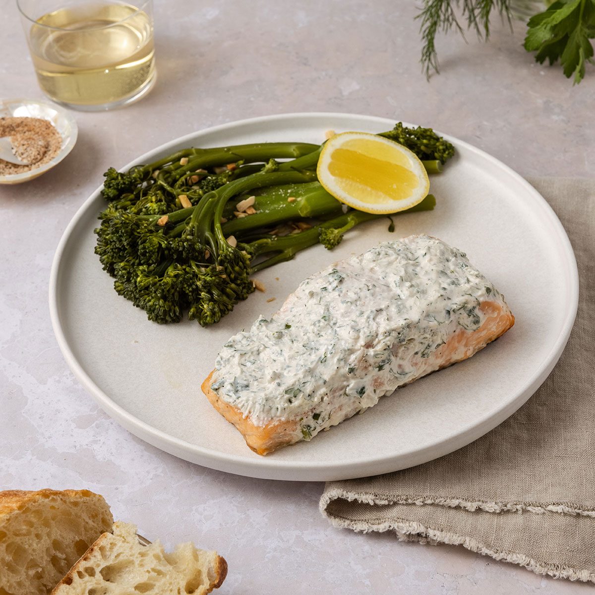 Creamy herb grilled salmon served on plate with side of broccolini and lemon.