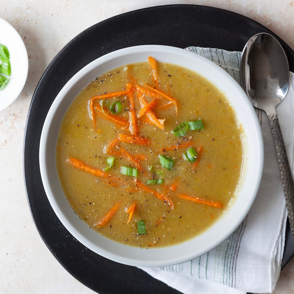 Two servings of Taste of Home Vegetarian Split Pea Soup garnished with shredded carrots and sliced green onions