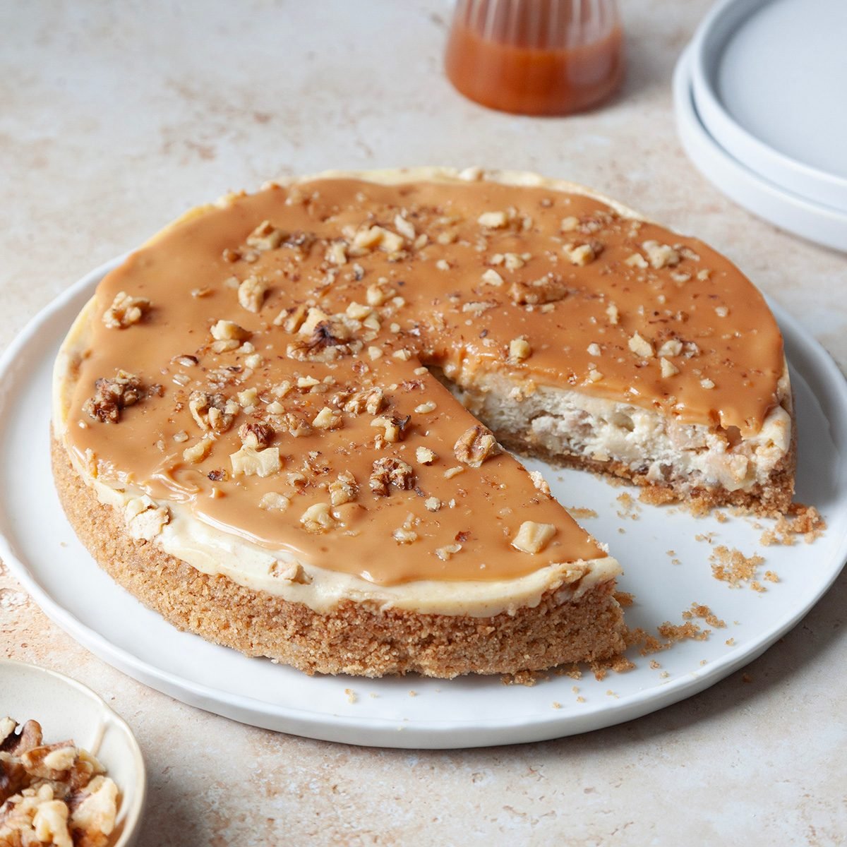 Full yield of Taste of Home Caramel Apple Cheesecake with a slice out, small pitcher of caramel sauce in the background Sarahtramonte 7