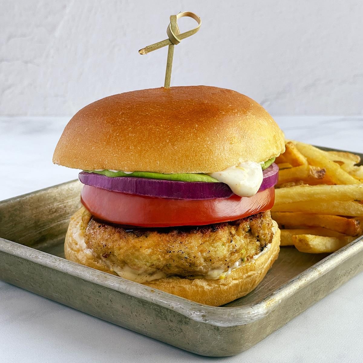 Taste of Home's shrimp burger with buns, lettuce, onion, tomato and fries.