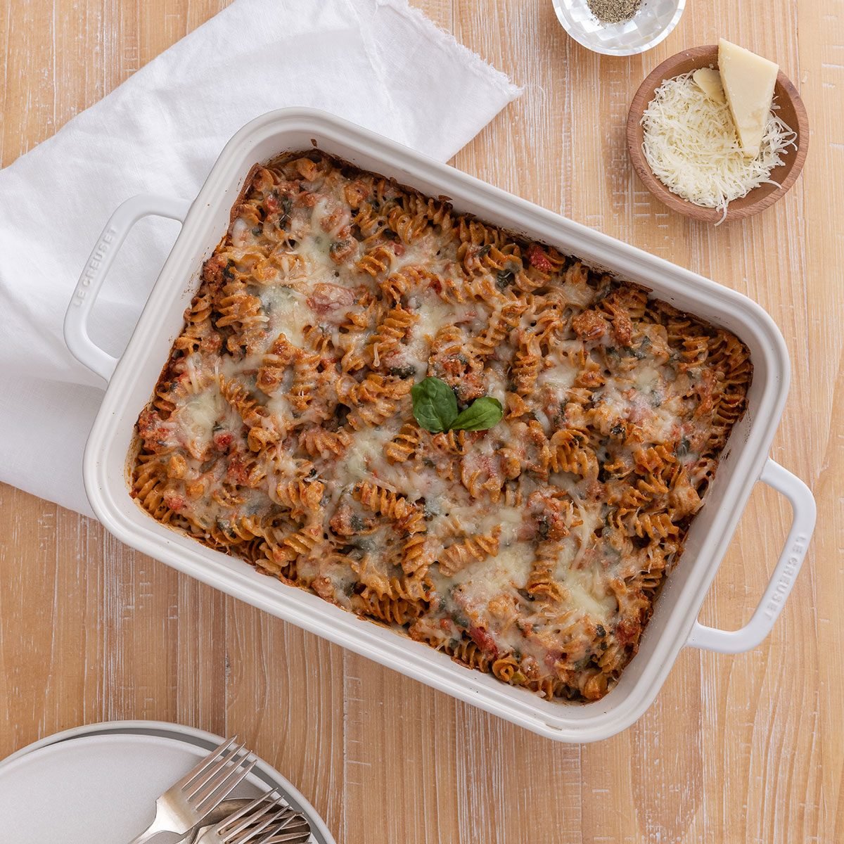 Sausage spinach pasta bake in baking dish served on wooden table.