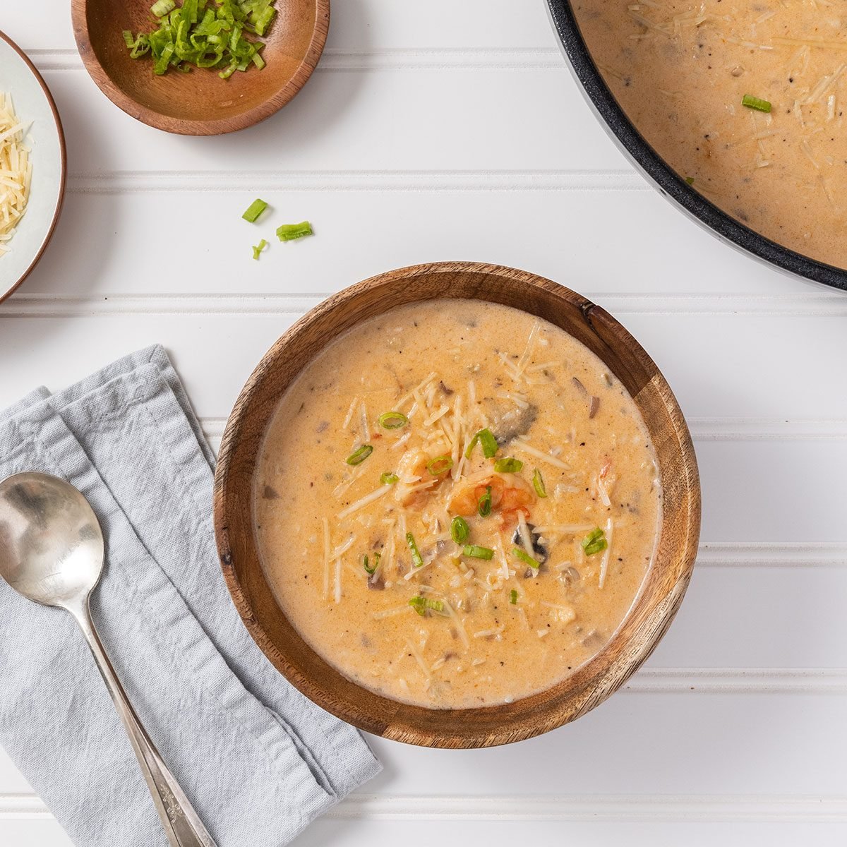 Seafood bisque bowl served on a bowl and sides of shredded cheese and green onions.