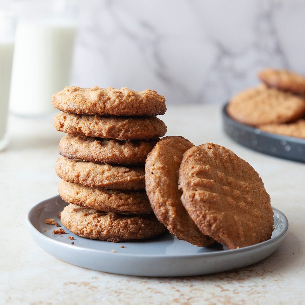 Stack of Taste of Home Gluten-Free Peanut Butter Cookies with two glasses of milk in the background