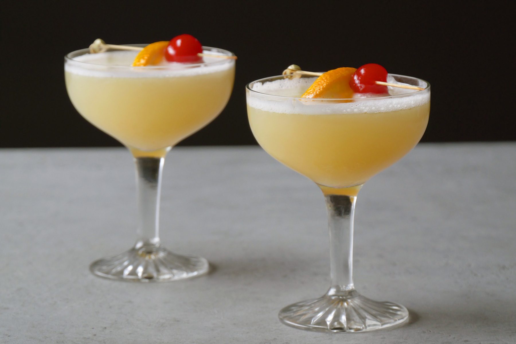 Two cocktail glasses of Whiskey Sour on a table