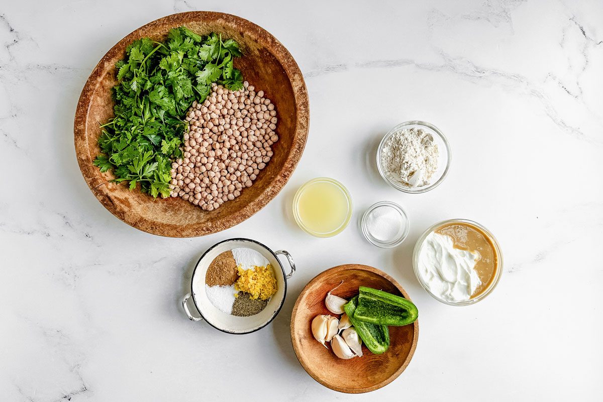 Ingredients for Taste of Home falafel burgers in bowls on a marble surface.