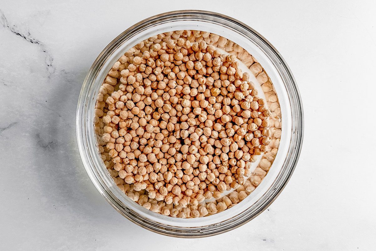 Garbanzo beans in water in a glass bowl for Taste of Home falafel burgers.