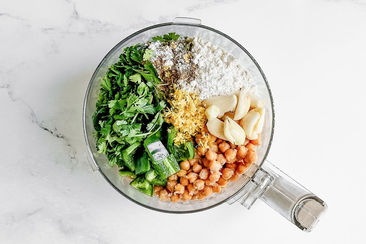 Ingredients for Taste of Home falafel burgers in a food processor on a marble surface