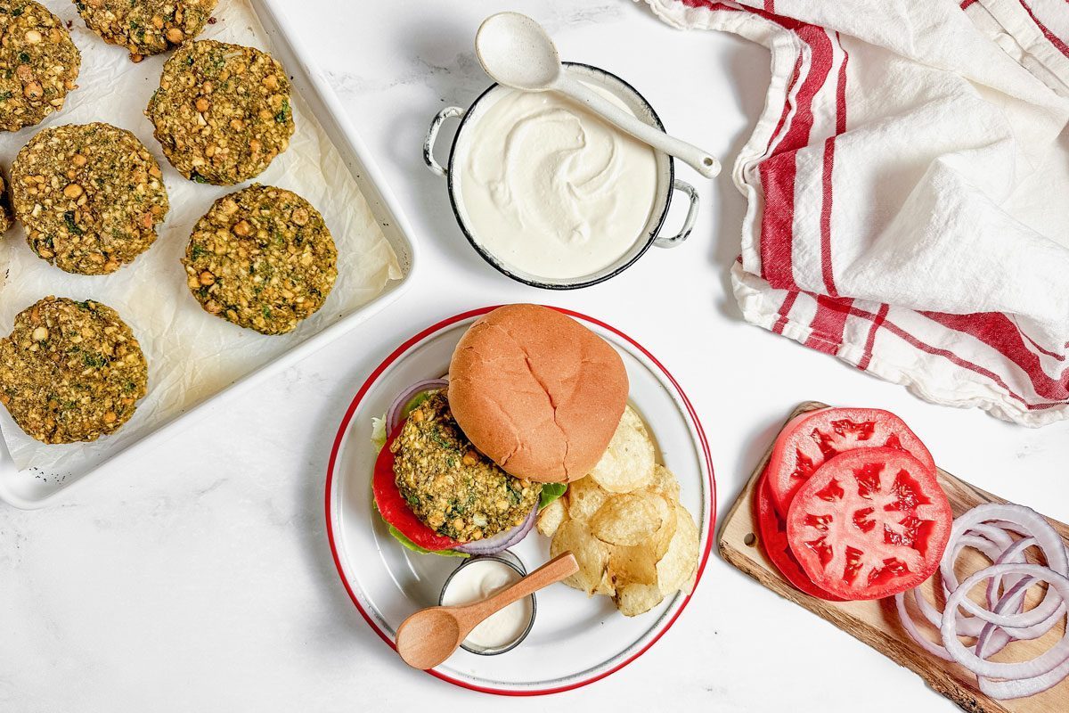 Taste of Home Falafel Burgers with tahini yogurt sauce on an enamel plate with potato chips.