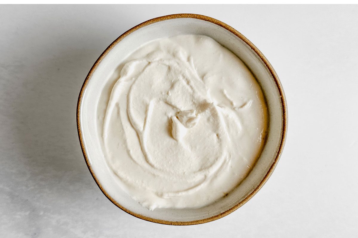 Yogurt tahini dressing for Taste of Home Falafel Burgers in a ceramic bowl on a marble surface.