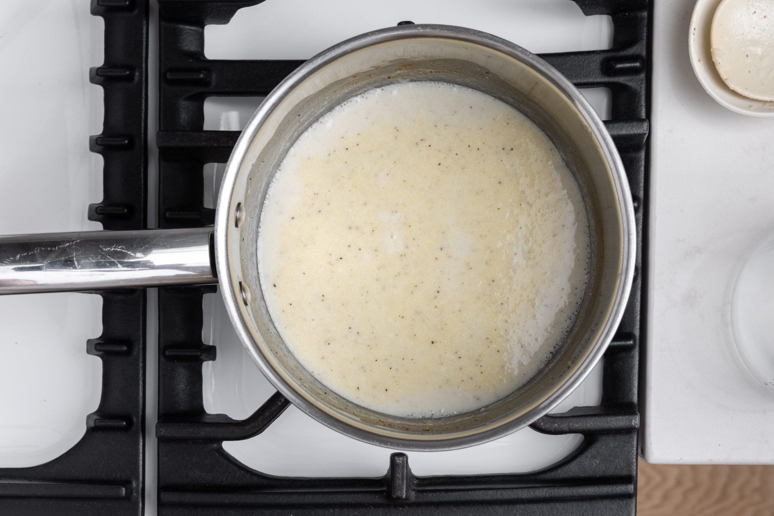 Bechamel sauce being prepared in sauce pan.