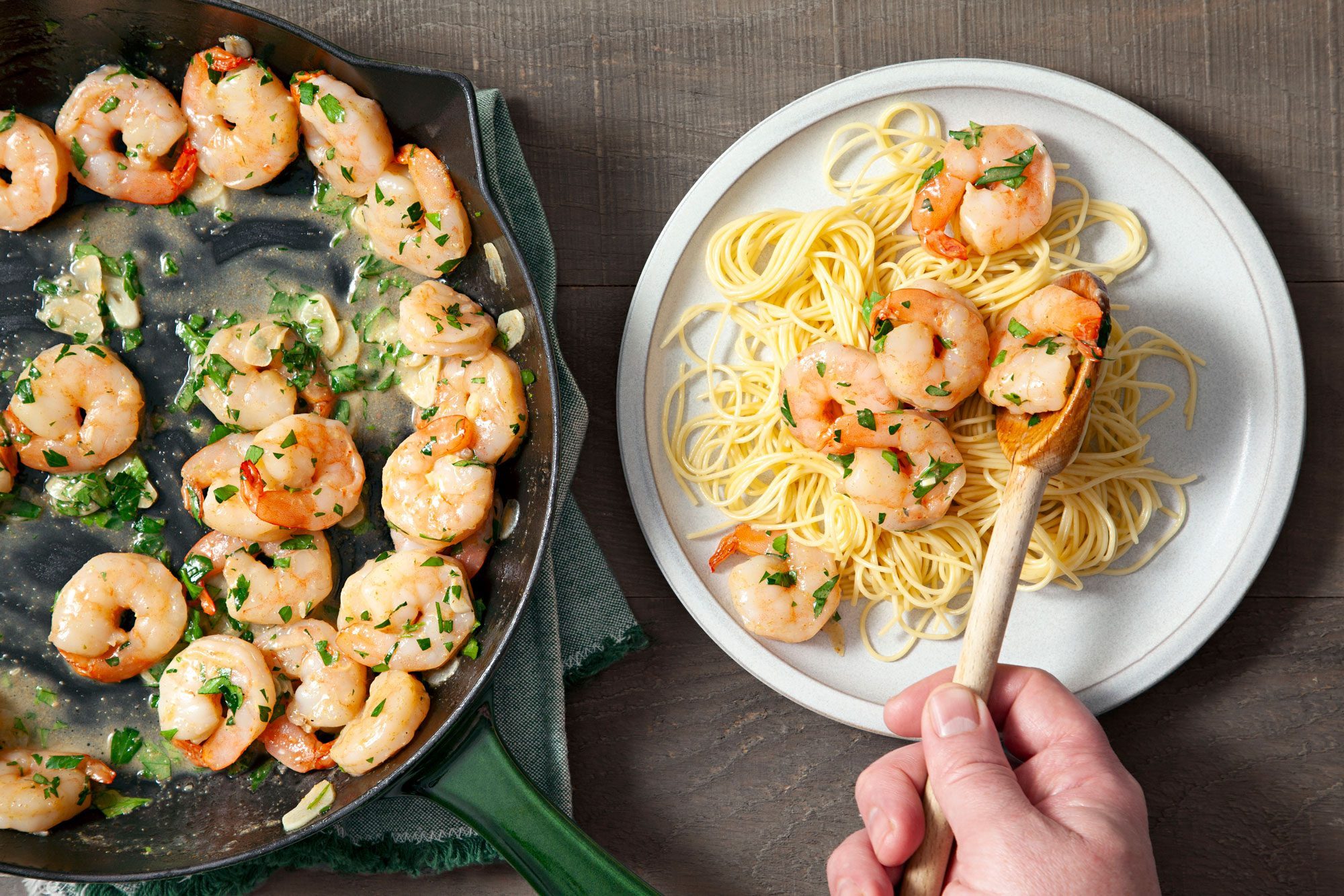 Overhead shot of Garlic Lemon Shrimp; served hot with pasta; napkin; wooden background;