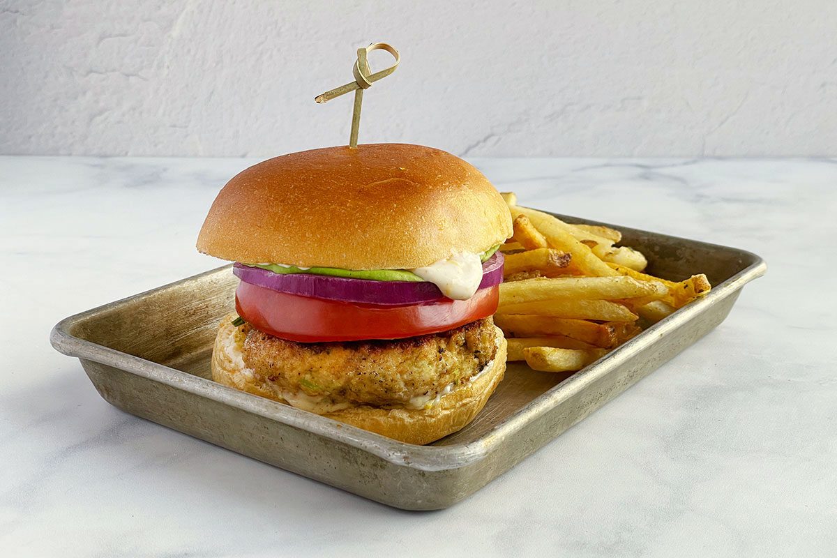 Taste of Home's shrimp burger with buns, lettuce, onion, tomato and fries.